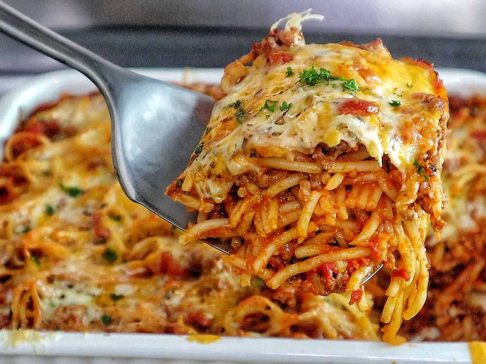 Cheesy baked spaghetti casserole with seasoned ground beef, tomato sauce, and melted mozzarella, cheddar, and parmesan.