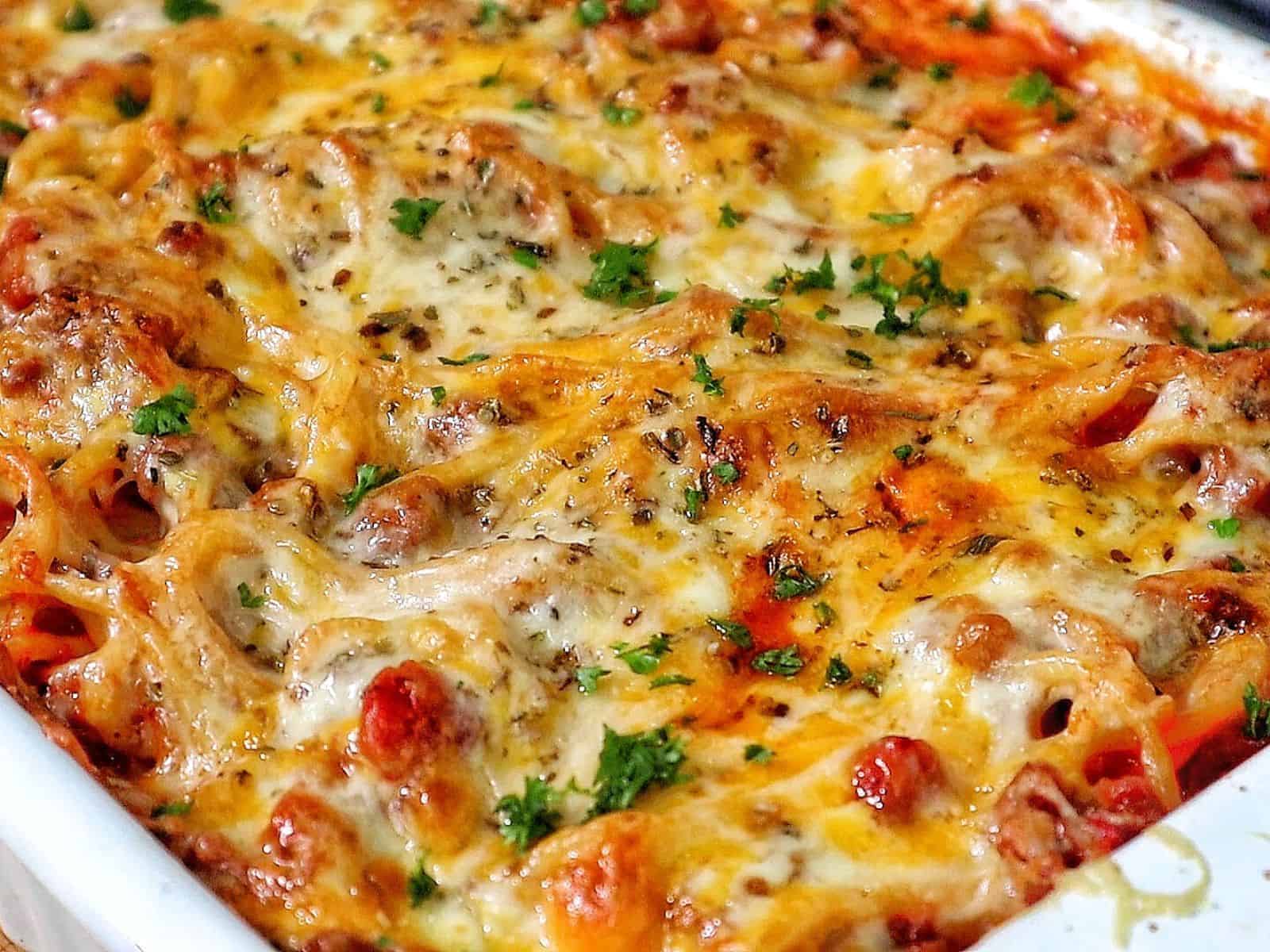 Cheesy baked spaghetti casserole with seasoned ground beef, tomato sauce, and melted mozzarella, cheddar, and parmesan.