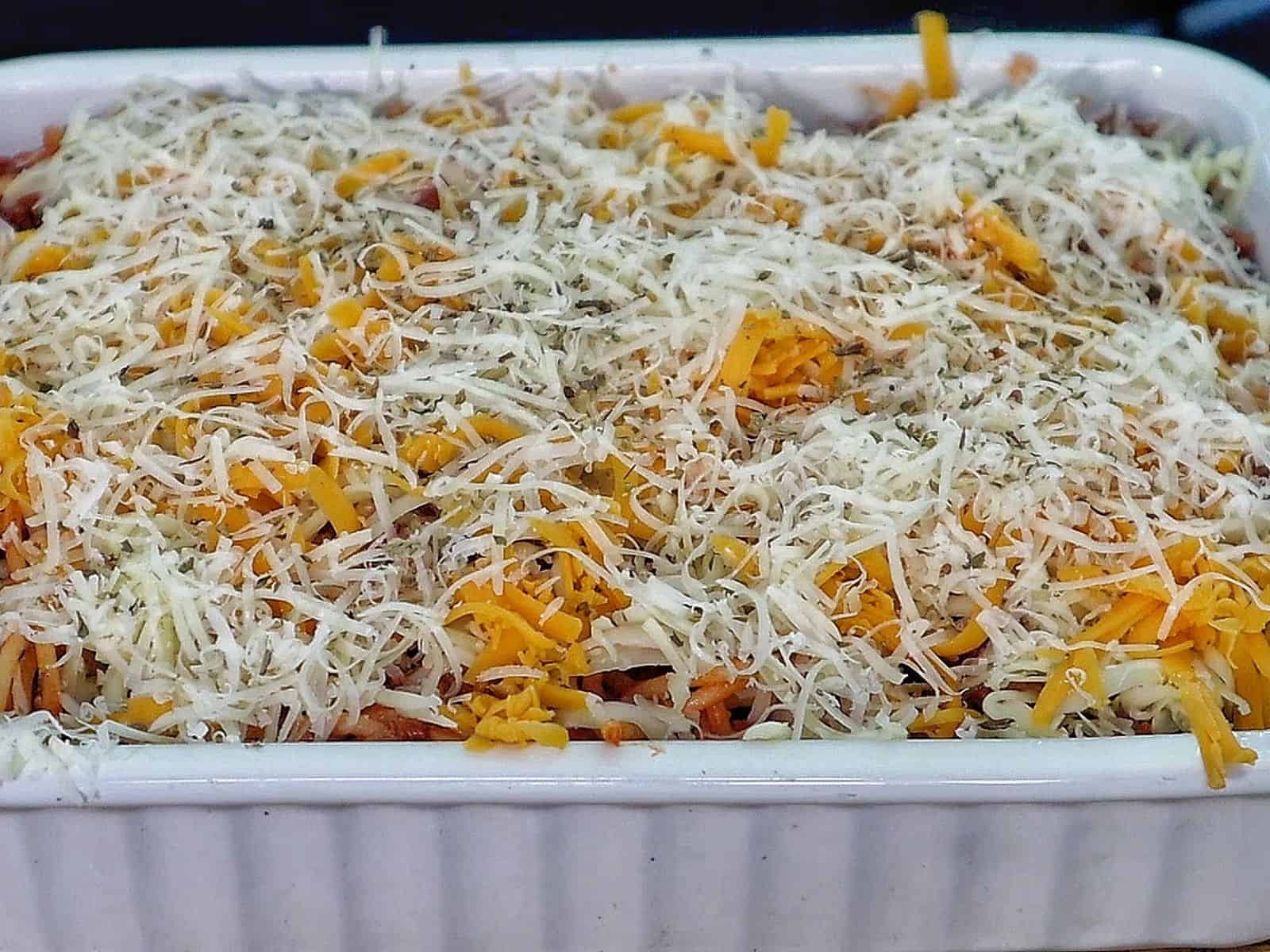 Cheesy baked spaghetti casserole with seasoned ground beef, tomato sauce, and melted mozzarella, cheddar, and parmesan.