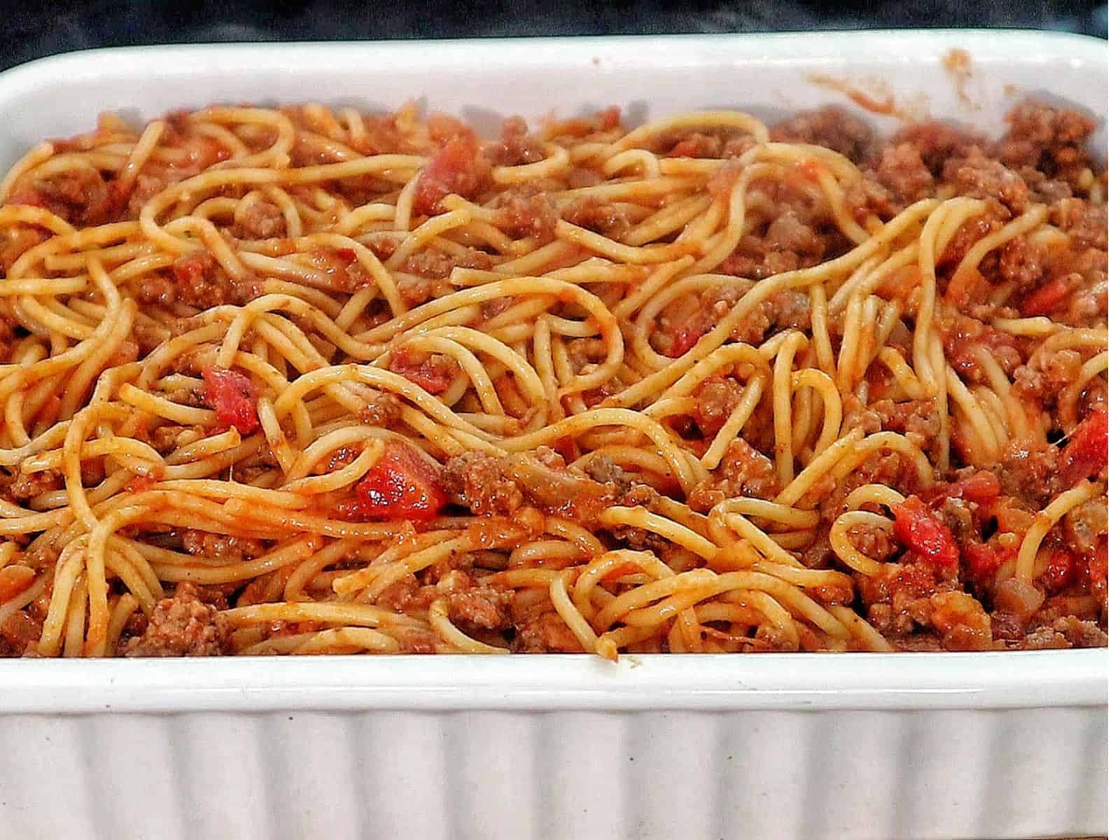 Cheesy baked spaghetti casserole with seasoned ground beef, tomato sauce, and melted mozzarella, cheddar, and parmesan.