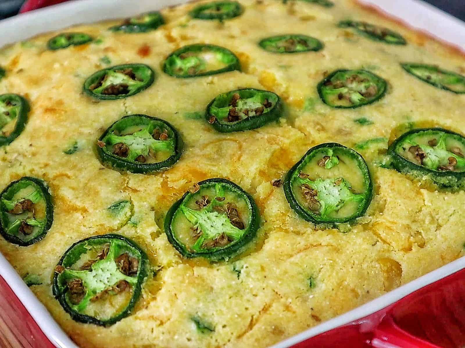 Golden cheesy jalapeño cornbread slice topped with fresh jalapeño rounds, baked until crispy on top and soft inside.