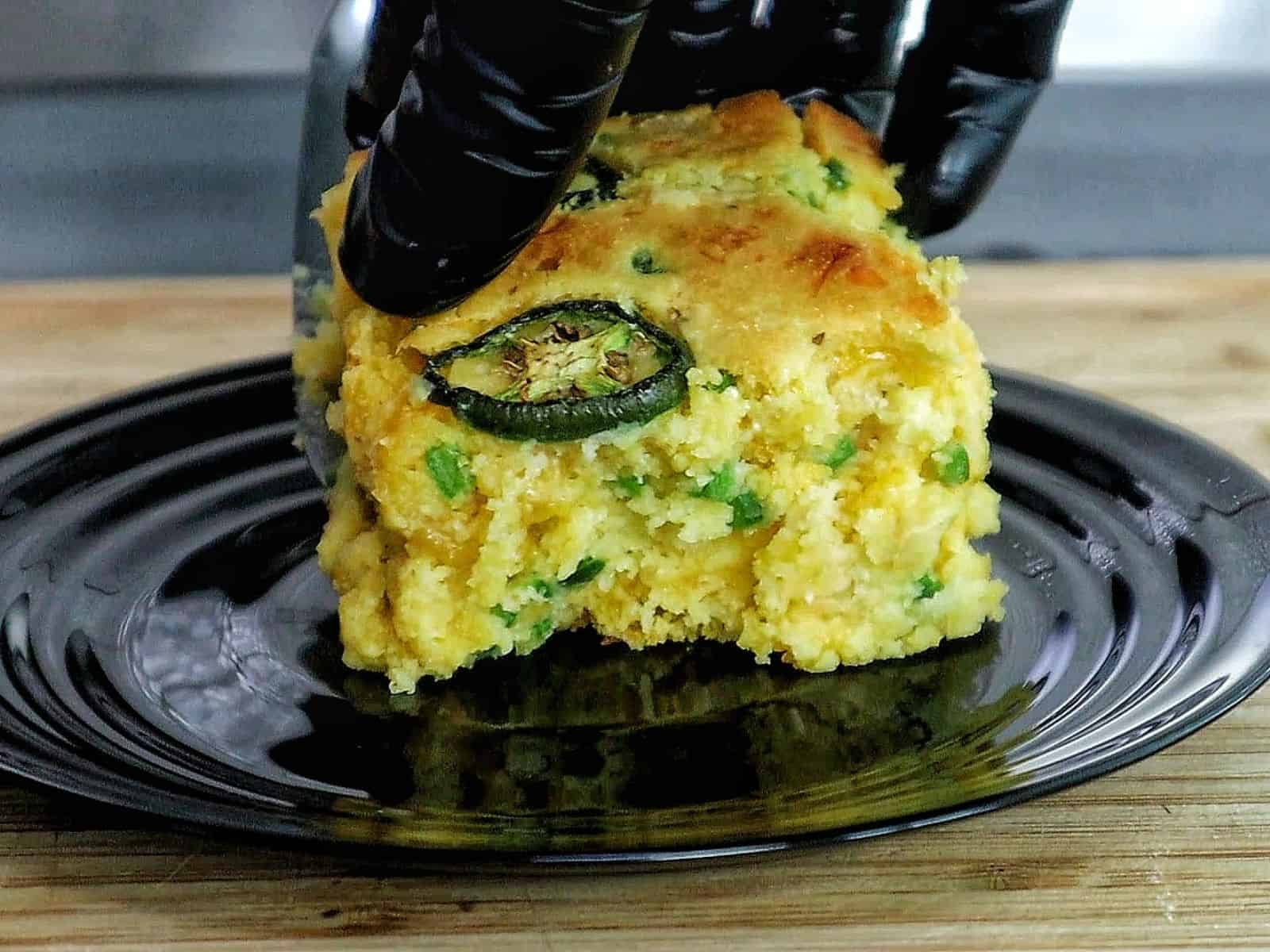 Golden cheesy jalapeño cornbread slice topped with fresh jalapeño rounds, baked until crispy on top and soft inside.
