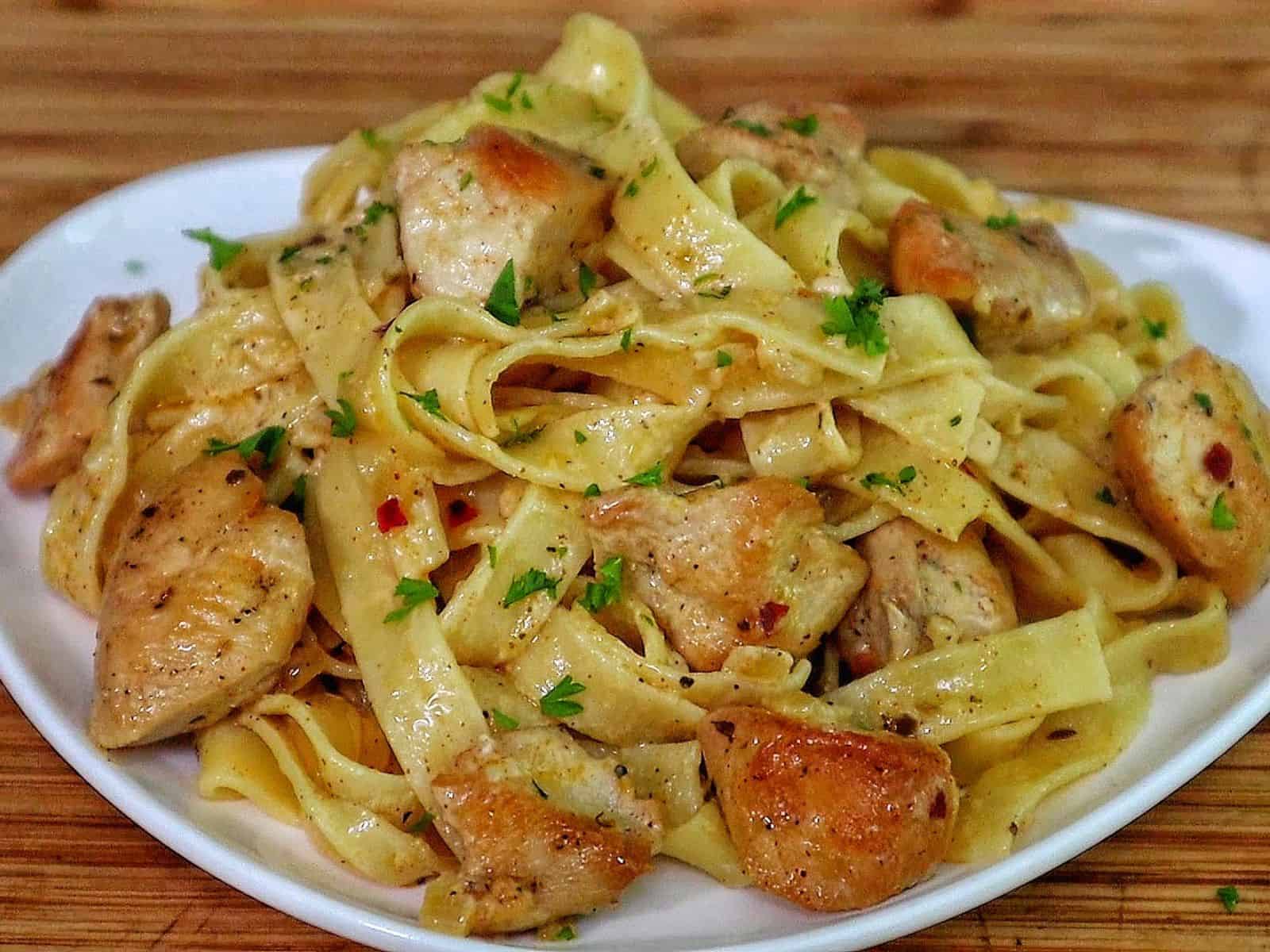 Creamy cowboy butter chicken pasta with tender seared chicken pieces tossed with fettuccine noodles in a rich buttery garlic cream sauce and garnished with fresh parsley.