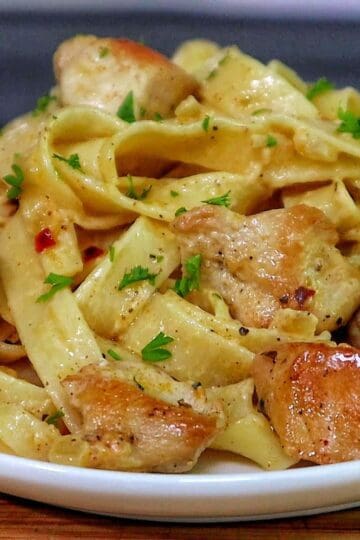 Creamy cowboy butter chicken pasta with tender seared chicken pieces tossed with fettuccine noodles in a rich buttery garlic cream sauce and garnished with fresh parsley.