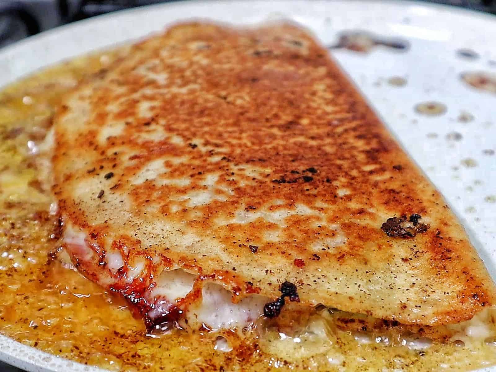 Toasted Italian sub wrap sliced in half, filled with layers of ham, salami, pepperoni, melted provolone cheese, lettuce, tomatoes, onions, and banana peppers.