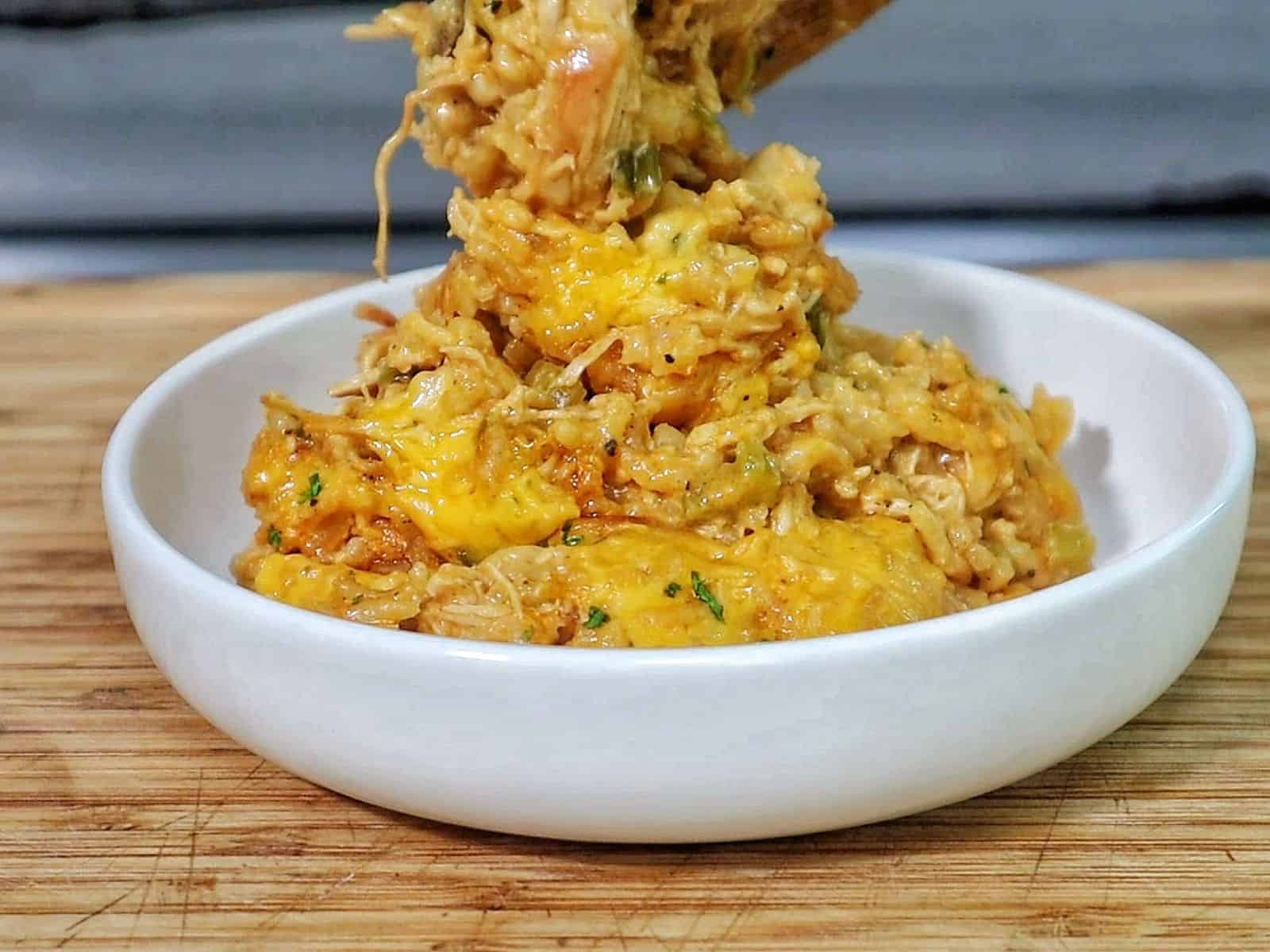 A skillet filled with cheesy buffalo chicken and rice, topped with melted cheddar cheese and herbs.