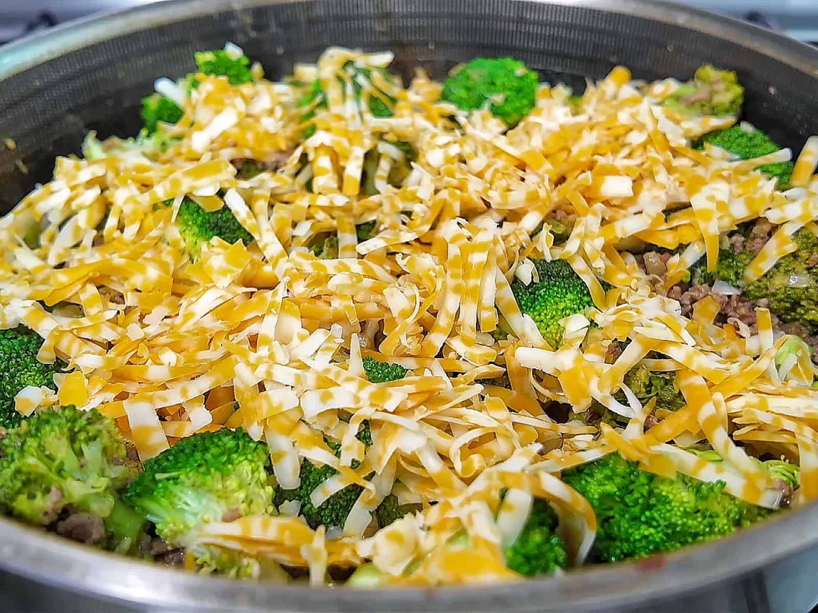 Cheesy ground beef and broccoli skillet with melted cheddar and colby jack cheese, cooked in a pan.