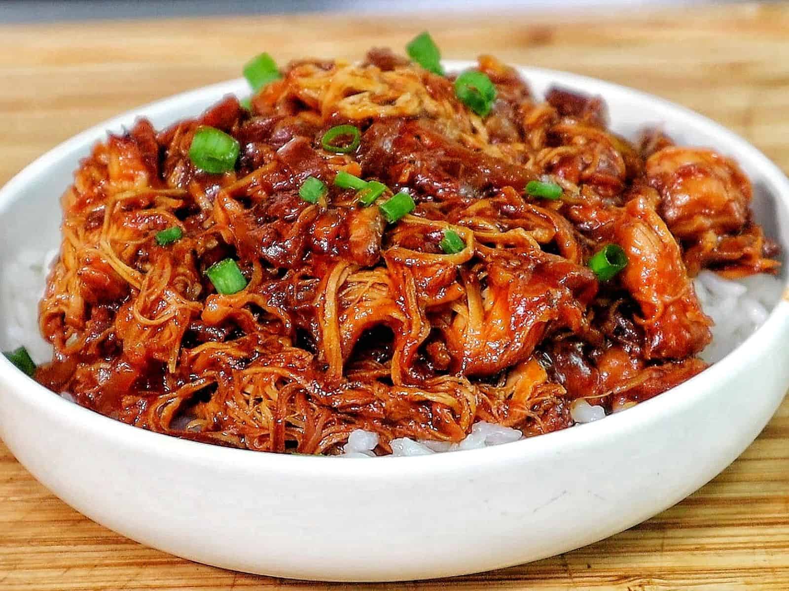 Shredded crockpot BBQ chicken coated in a rich Sweet Baby Ray’s sauce, served over white rice and topped with chopped green onions.