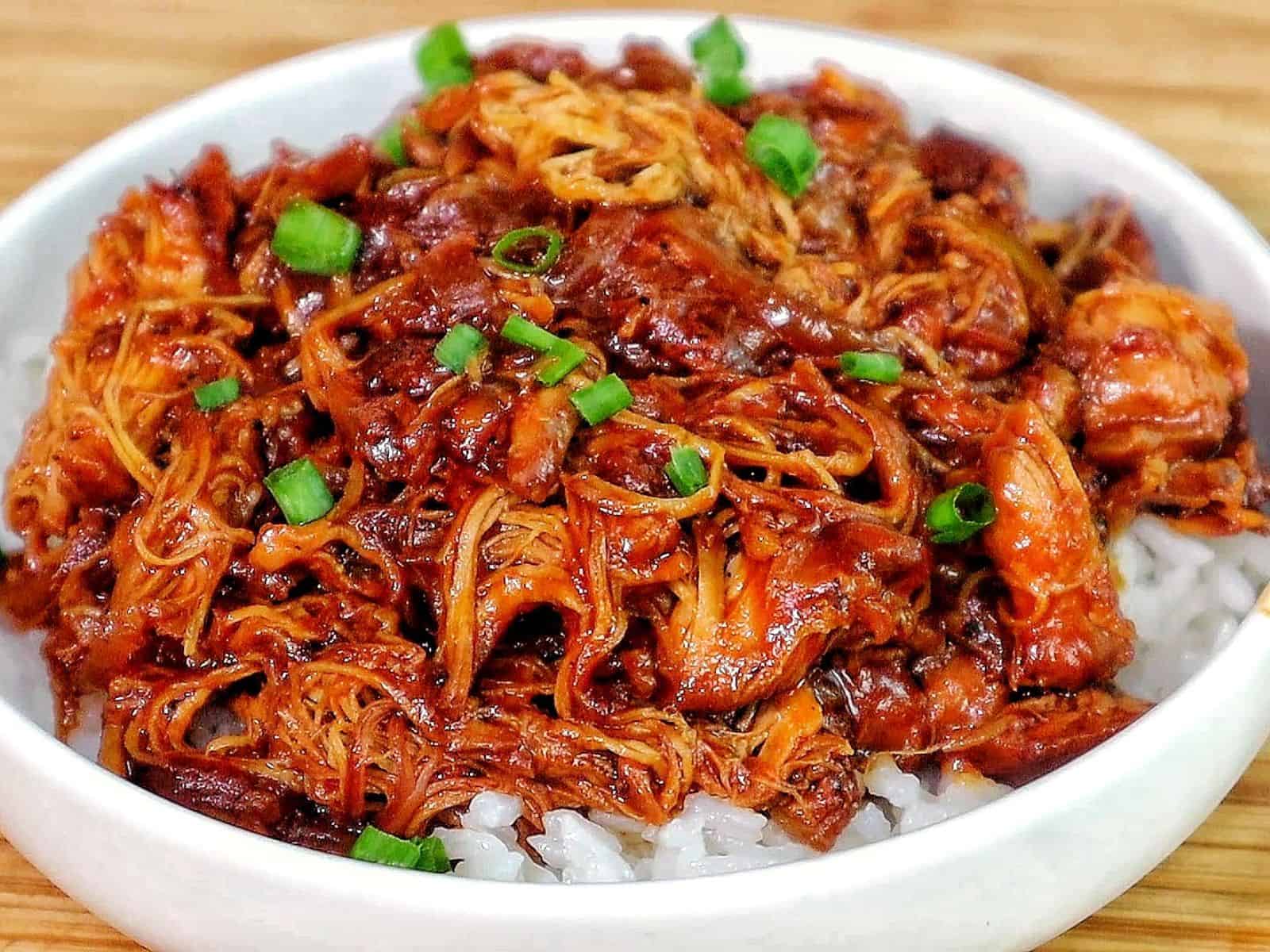 Shredded crockpot BBQ chicken coated in a rich Sweet Baby Ray’s sauce, served over white rice and topped with chopped green onions.