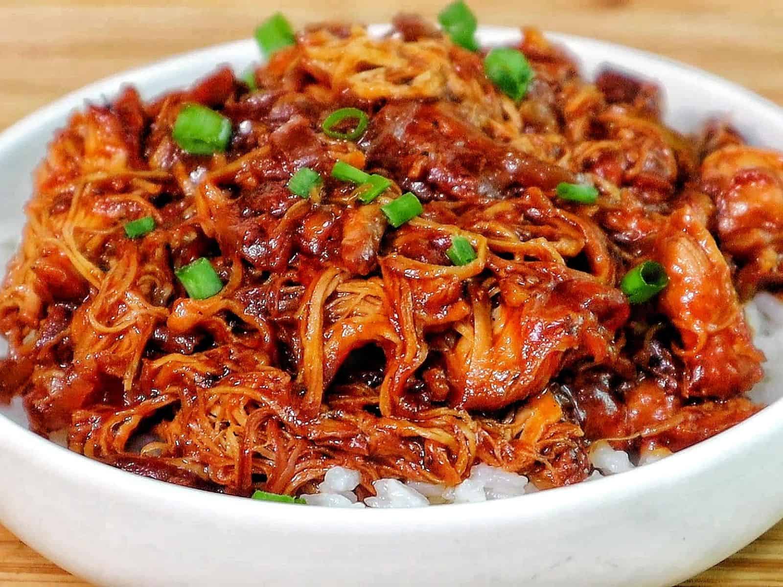 Shredded crockpot BBQ chicken coated in a rich Sweet Baby Ray’s sauce, served over white rice and topped with chopped green onions.