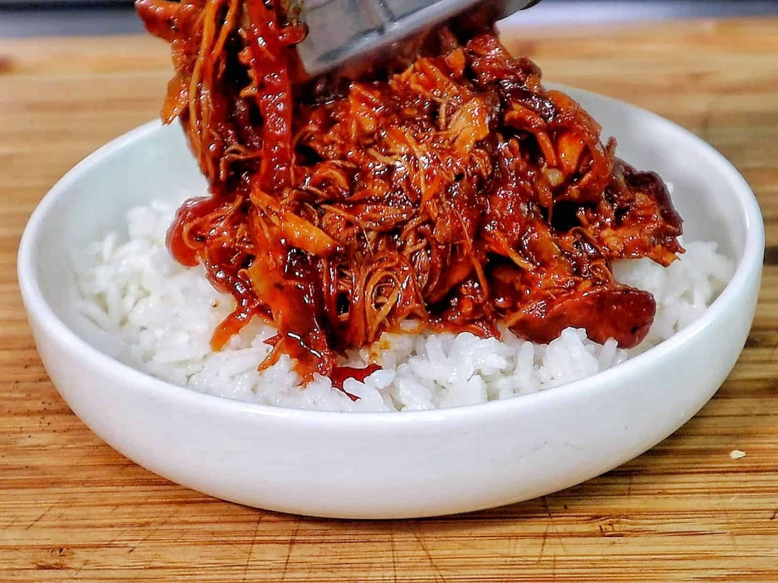 Shredded crockpot BBQ chicken coated in a rich Sweet Baby Ray’s sauce, served over white rice and topped with chopped green onions.