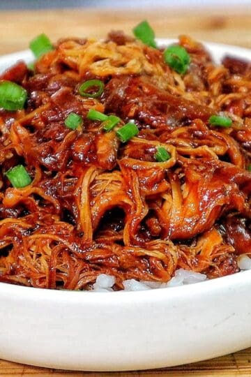 Shredded crockpot BBQ chicken coated in a rich Sweet Baby Ray’s sauce, served over white rice and topped with chopped green onions.