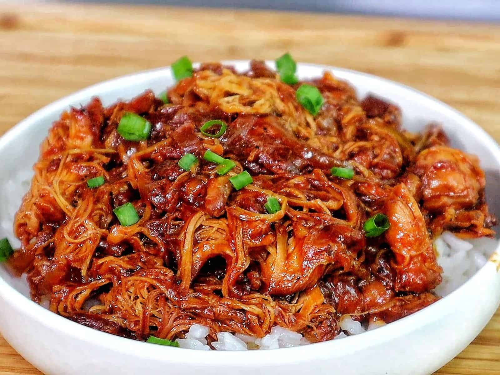 Shredded crockpot BBQ chicken coated in a rich Sweet Baby Ray’s sauce, served over white rice and topped with chopped green onions.