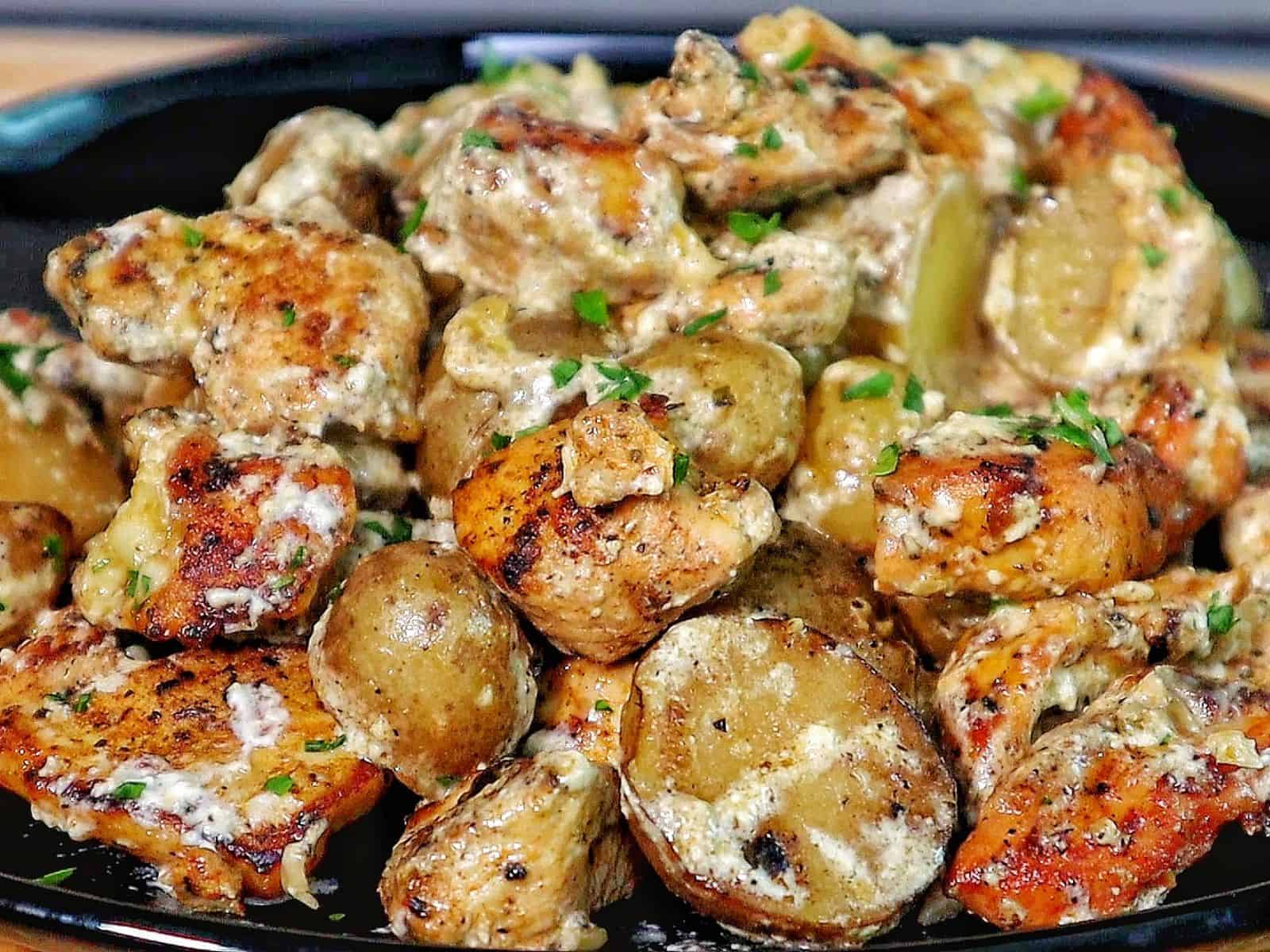 Creamy garlic parmesan chicken and baby potatoes, seared and coated in a rich sauce, garnished with parsley.
