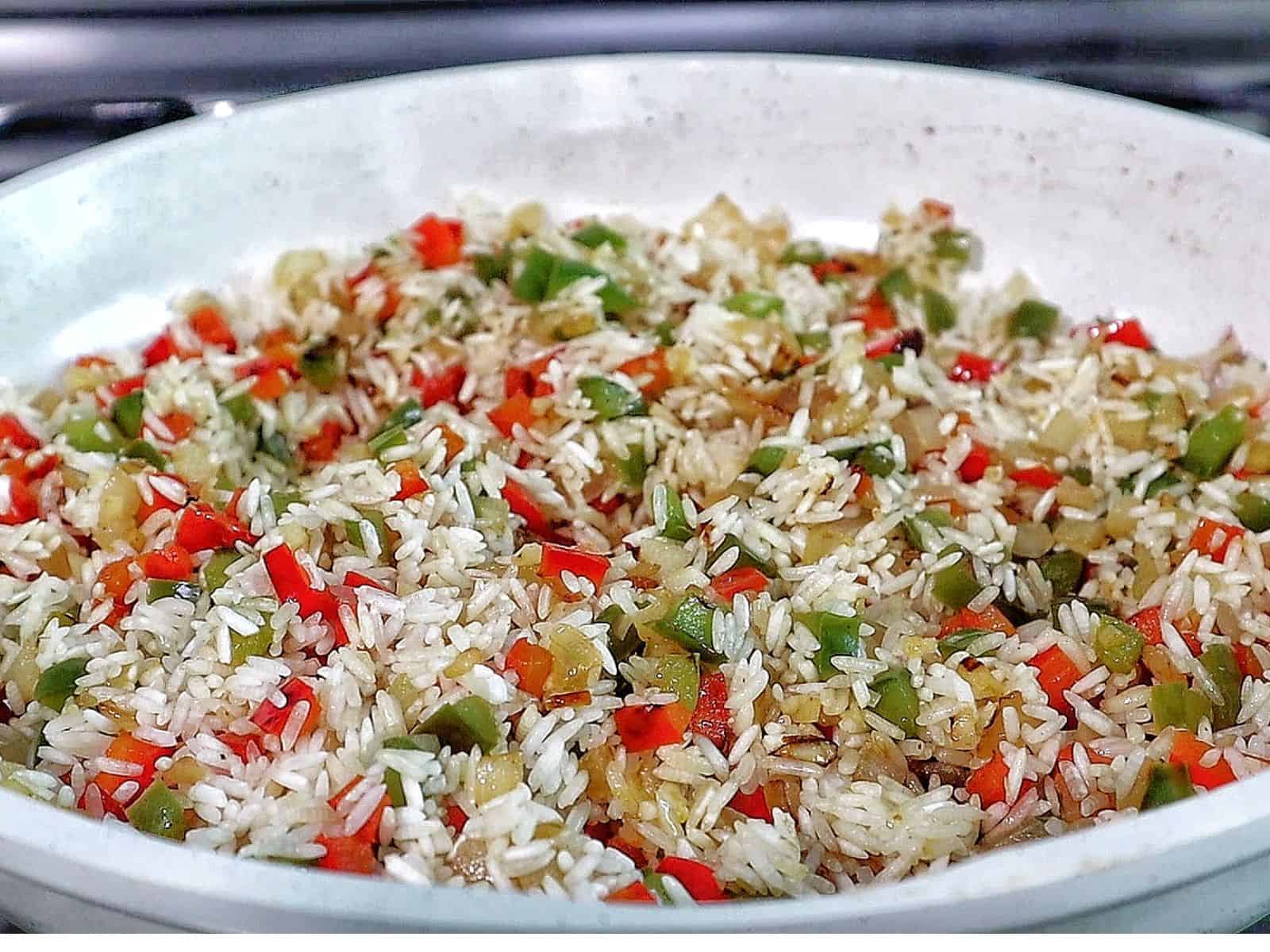 Honey garlic sausage and rice in a skillet with browned sausage slices, seasoned rice, bell peppers, and fresh parsley garnish.