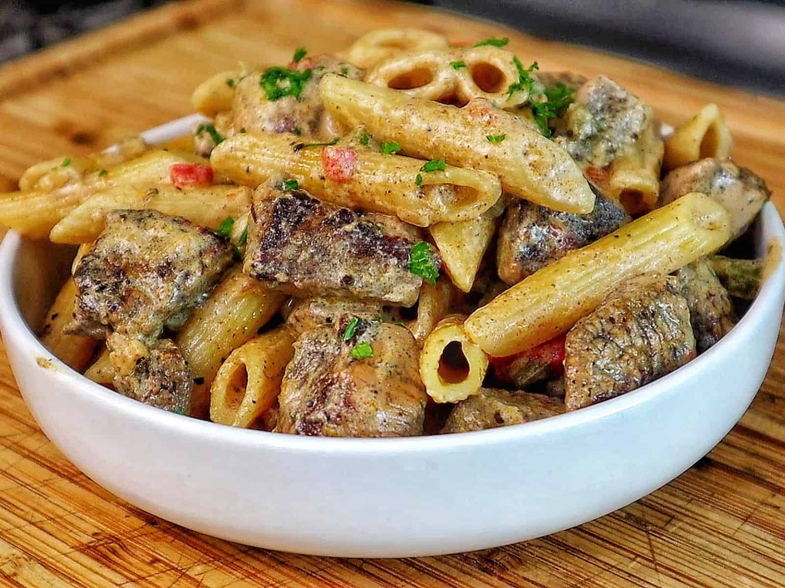 Creamy Rasta Pasta with jerk chicken made with penne pasta, seasoned chicken, colorful peppers, and a rich creamy jerk sauce garnished with fresh parsley.