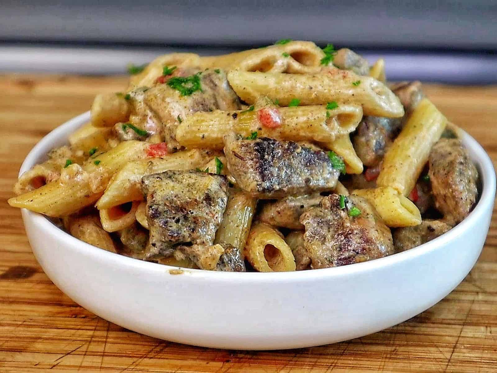 Creamy Rasta Pasta with jerk chicken made with penne pasta, seasoned chicken, colorful peppers, and a rich creamy jerk sauce garnished with fresh parsley.