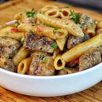 Creamy Rasta Pasta with jerk chicken made with penne pasta, seasoned chicken, colorful peppers, and a rich creamy jerk sauce garnished with fresh parsley.