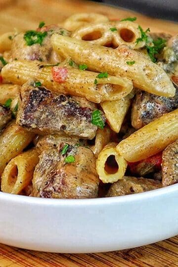 Creamy Rasta Pasta with jerk chicken made with penne pasta, seasoned chicken, colorful peppers, and a rich creamy jerk sauce garnished with fresh parsley.