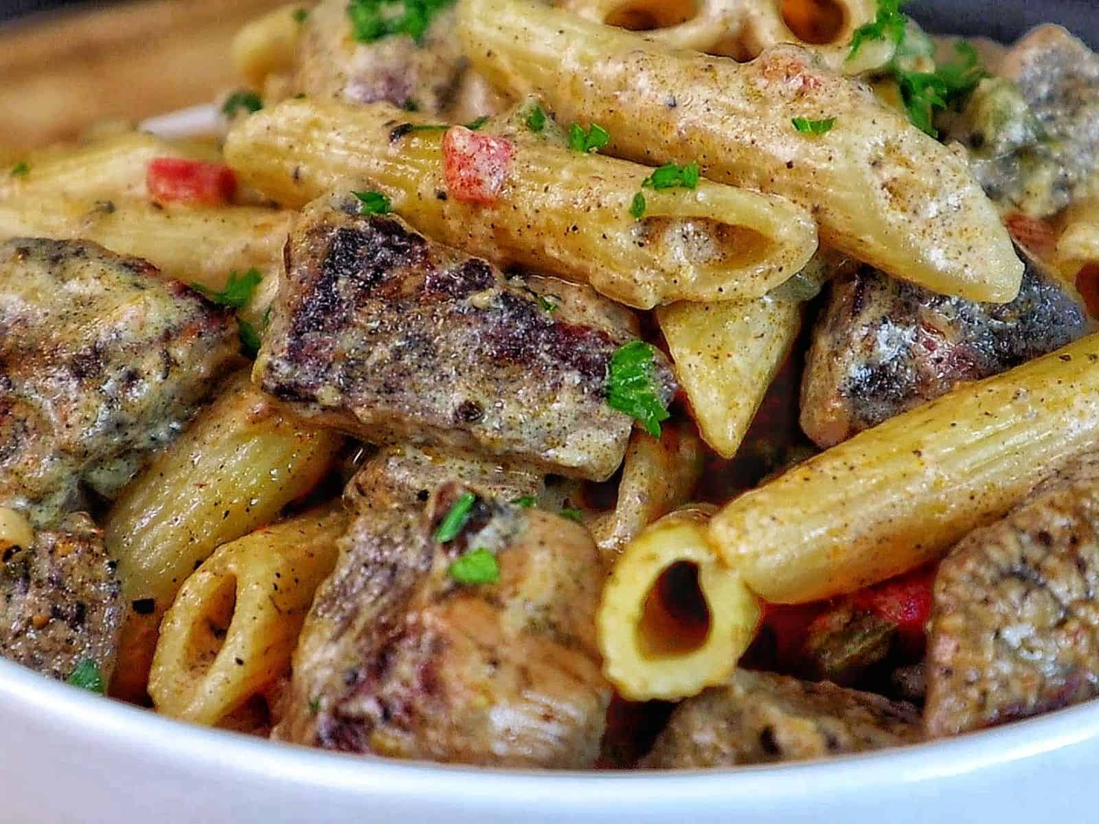 Creamy Rasta Pasta with jerk chicken made with penne pasta, seasoned chicken, colorful peppers, and a rich creamy jerk sauce garnished with fresh parsley.