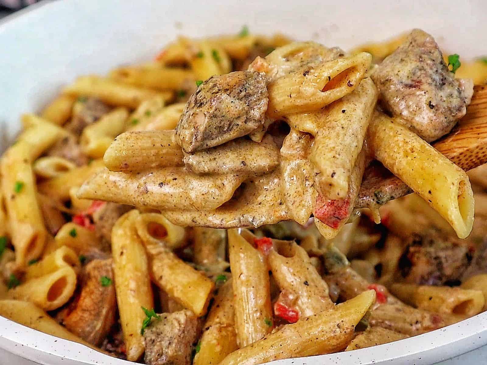 Creamy Rasta Pasta with jerk chicken made with penne pasta, seasoned chicken, colorful peppers, and a rich creamy jerk sauce garnished with fresh parsley.