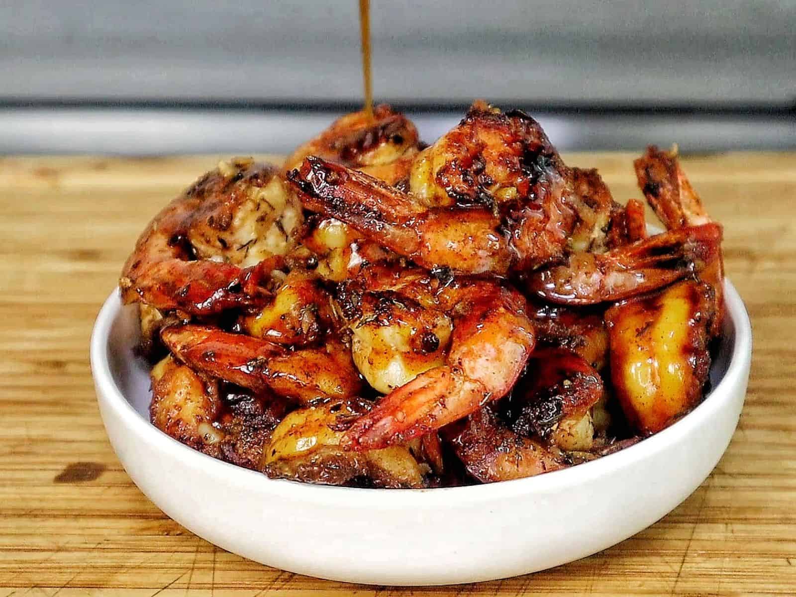 Bowl of hot honey garlic shrimp coated in a glossy sweet and spicy sauce, garnished with parsley.
