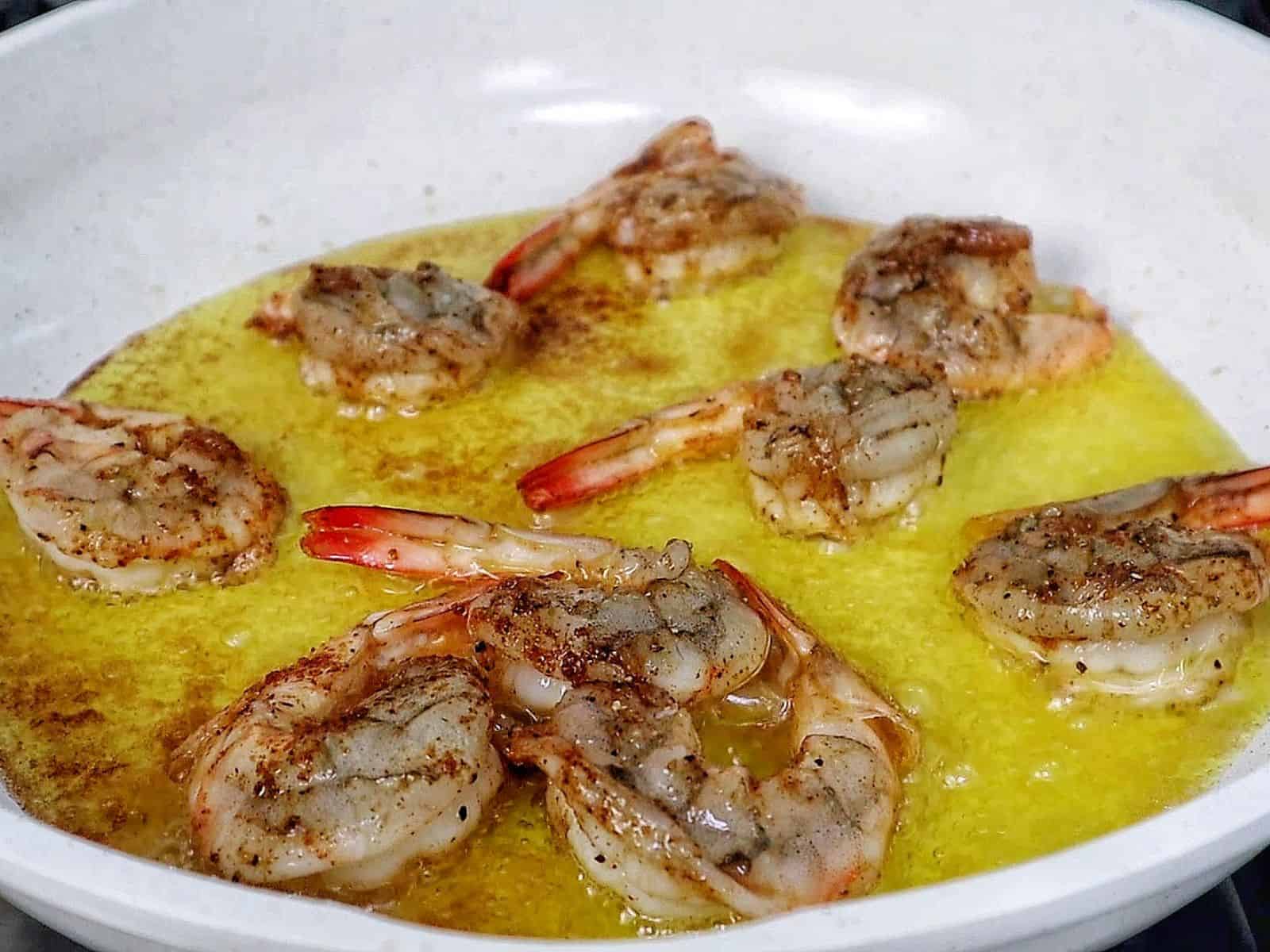 Bowl of hot honey garlic shrimp coated in a glossy sweet and spicy sauce, garnished with parsley.