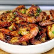 Bowl of hot honey garlic shrimp coated in a glossy sweet and spicy sauce, garnished with parsley.