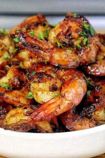 Bowl of hot honey garlic shrimp coated in a glossy sweet and spicy sauce, garnished with parsley.
