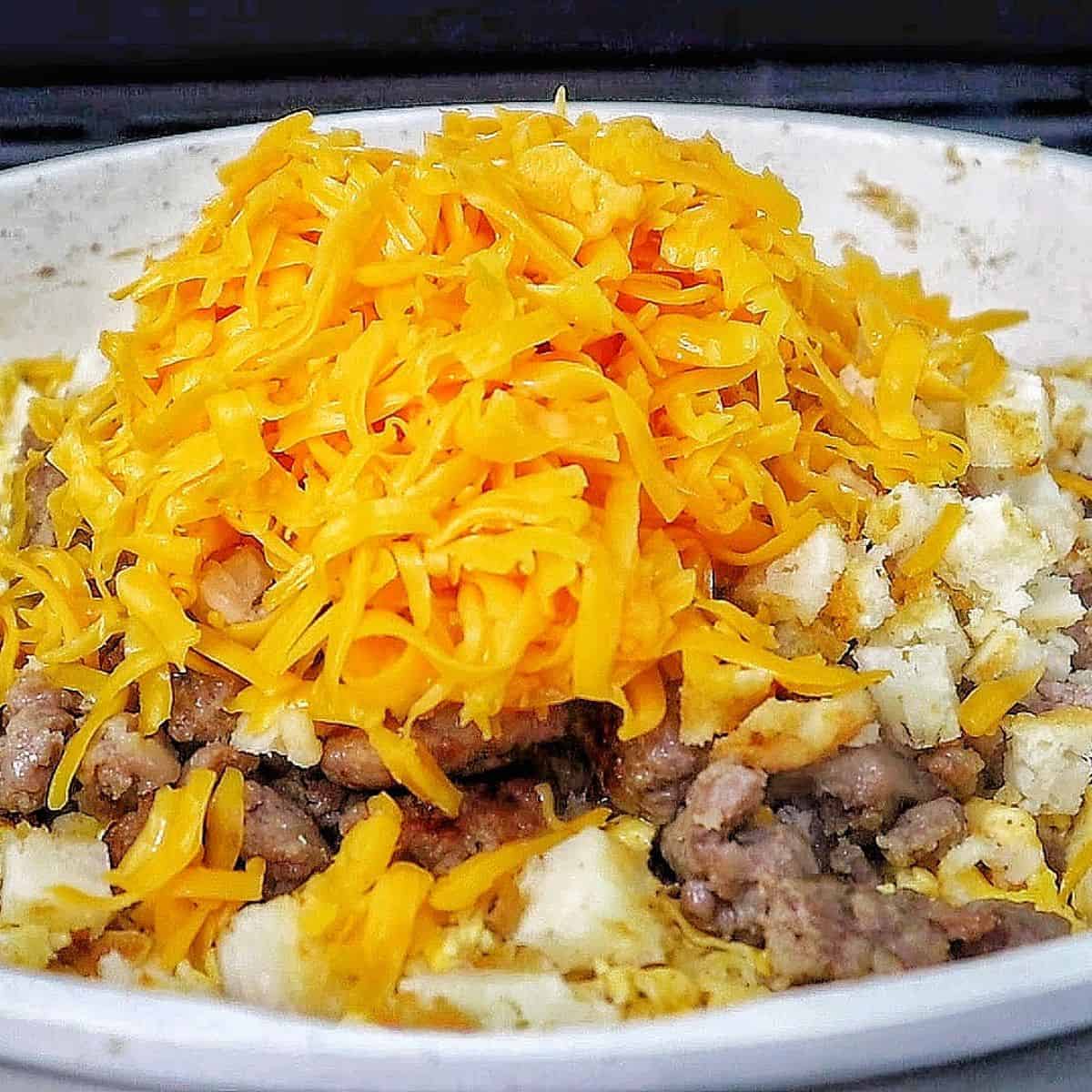 Breakfast enchiladas topped with creamy homemade sausage gravy and melted cheese. The enchiladas are stuffed with scrambled eggs, sausage, hash browns, and cheese.