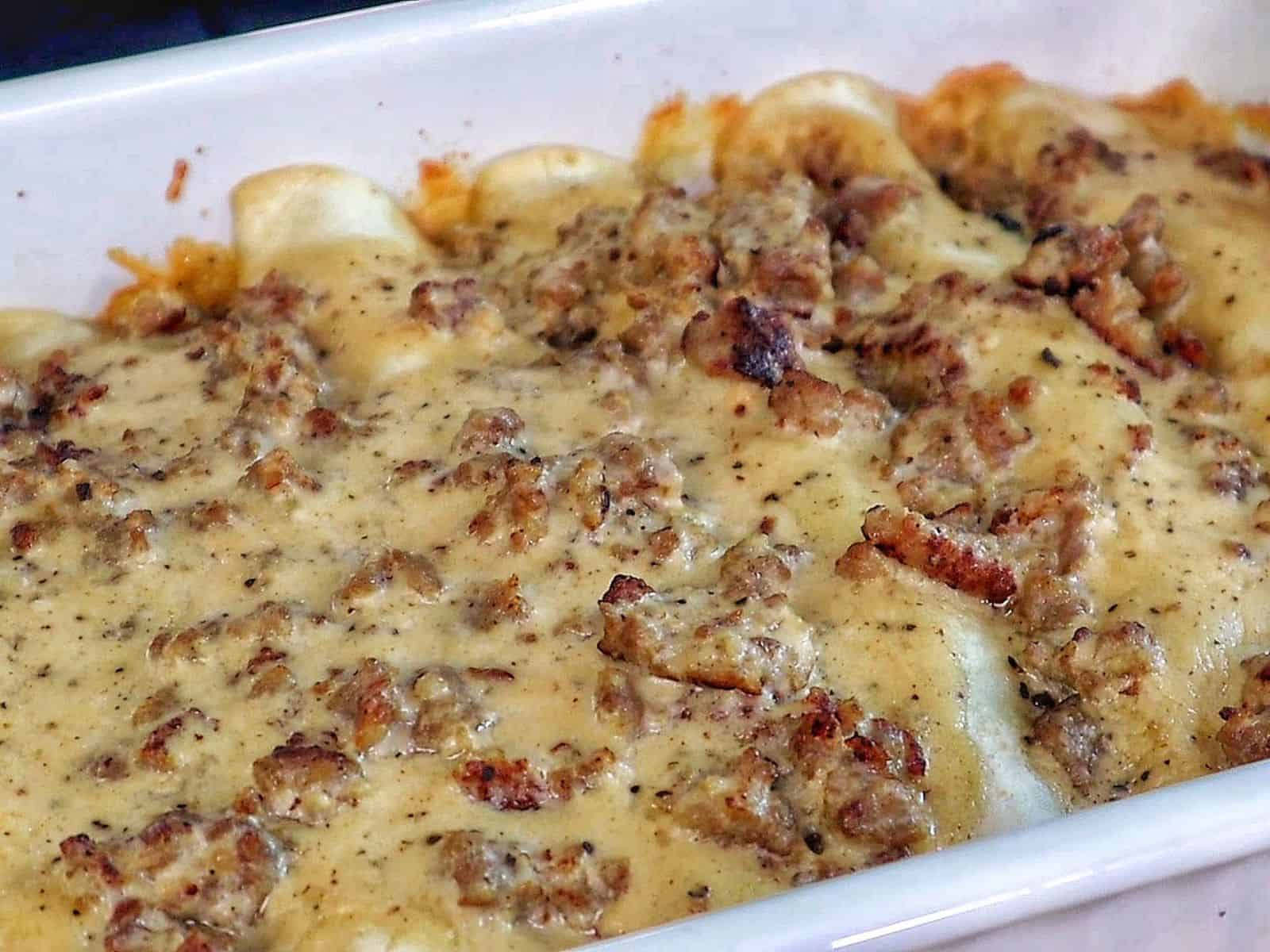 Breakfast enchiladas topped with creamy homemade sausage gravy and melted cheese. The enchiladas are stuffed with scrambled eggs, sausage, hash browns, and cheese.
