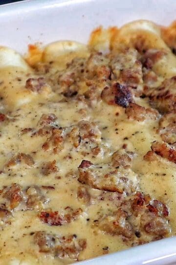 Breakfast enchiladas topped with creamy homemade sausage gravy and melted cheese. The enchiladas are stuffed with scrambled eggs, sausage, hash browns, and cheese.