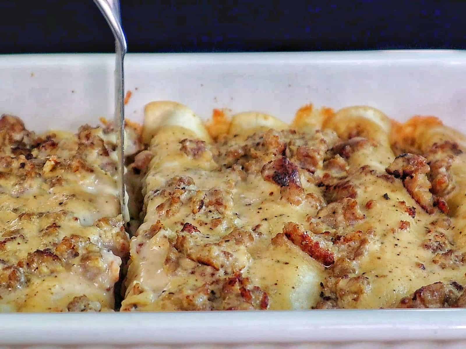 Breakfast enchiladas topped with creamy homemade sausage gravy and melted cheese. The enchiladas are stuffed with scrambled eggs, sausage, hash browns, and cheese.