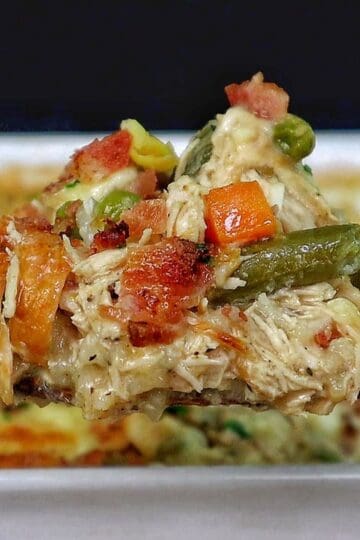 Creamy Chicken Alfredo Rice Casserole baked until golden and bubbly in a casserole dish, loaded with tender shredded chicken, peas, carrots, crispy bacon, melted mozzarella cheese, and a rich Alfredo sauce, garnished with fresh parsley.