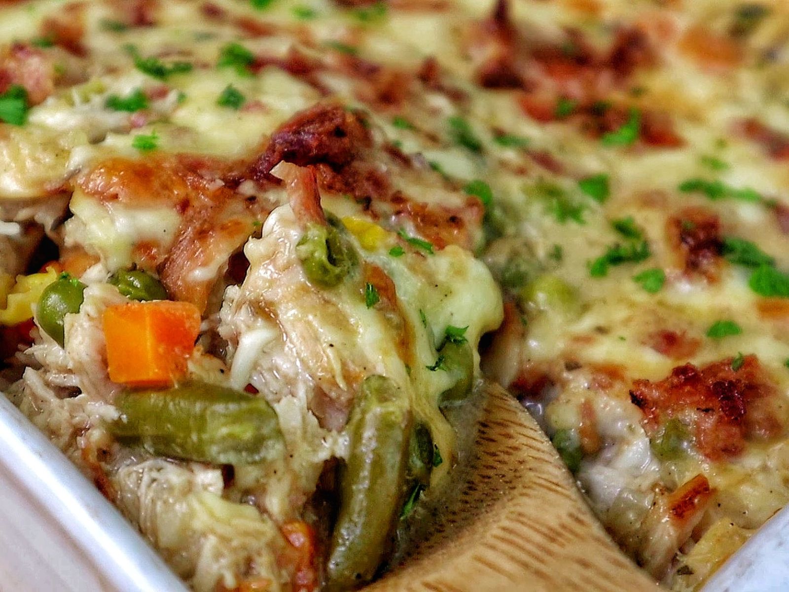 Creamy Chicken Alfredo Rice Casserole baked until golden and bubbly in a casserole dish, loaded with tender shredded chicken, peas, carrots, crispy bacon, melted mozzarella cheese, and a rich Alfredo sauce, garnished with fresh parsley.