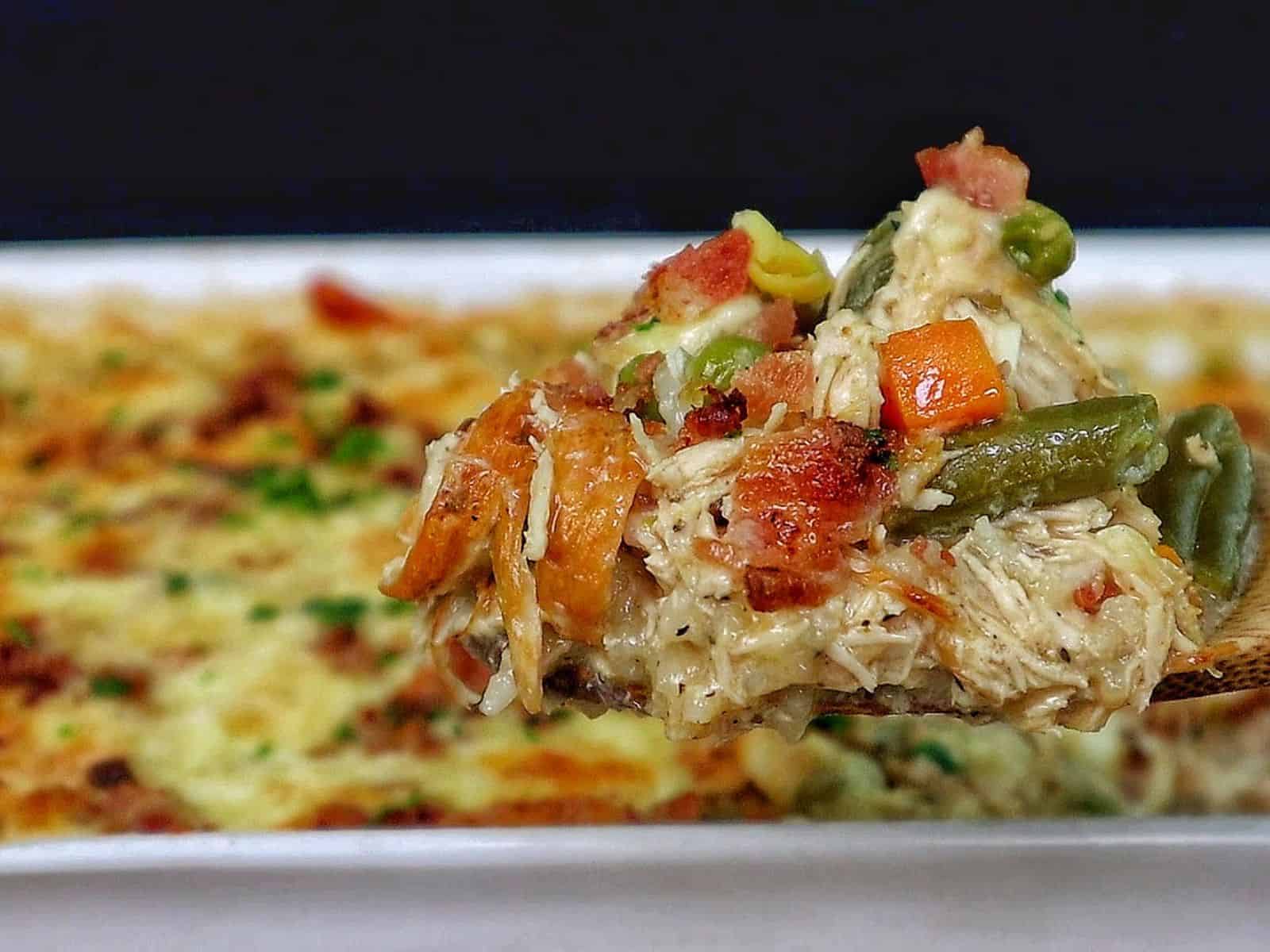 Creamy Chicken Alfredo Rice Casserole baked until golden and bubbly in a casserole dish, loaded with tender shredded chicken, peas, carrots, crispy bacon, melted mozzarella cheese, and a rich Alfredo sauce, garnished with fresh parsley.