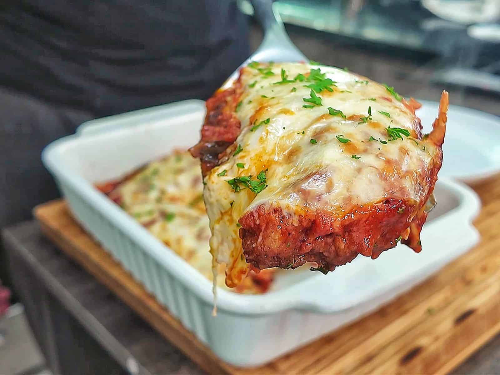 Chicken Parmesan baked in marinara sauce and topped with a thick layer of melted mozzarella cheese garnished with fresh parsley.