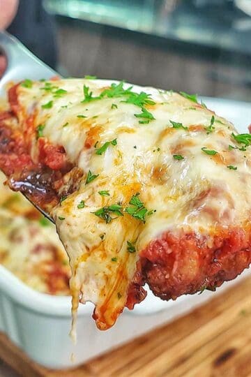 Chicken Parmesan baked in marinara sauce and topped with a thick layer of melted mozzarella cheese garnished with fresh parsley.