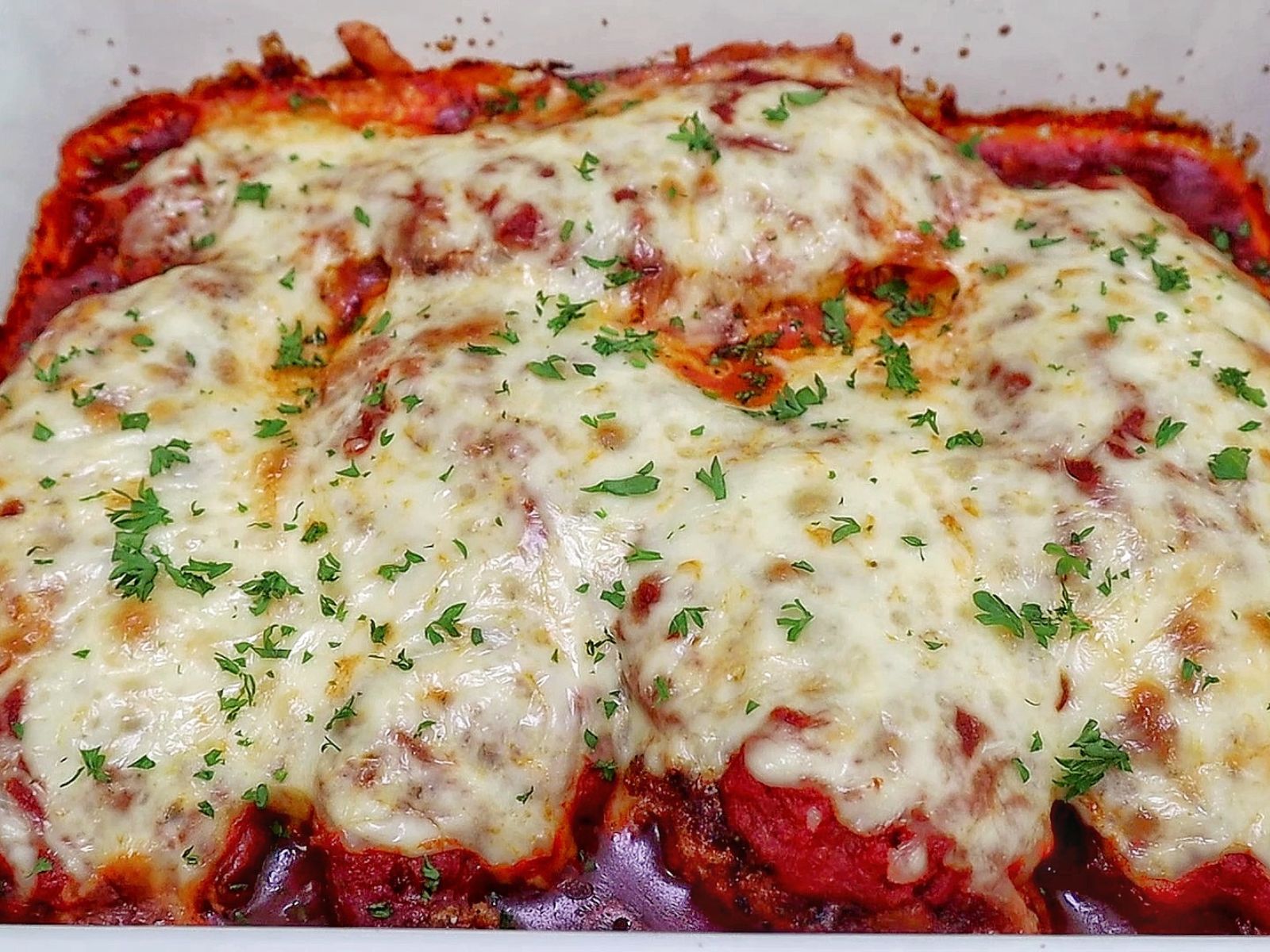 Chicken Parmesan baked in marinara sauce and topped with a thick layer of melted mozzarella cheese garnished with fresh parsley.