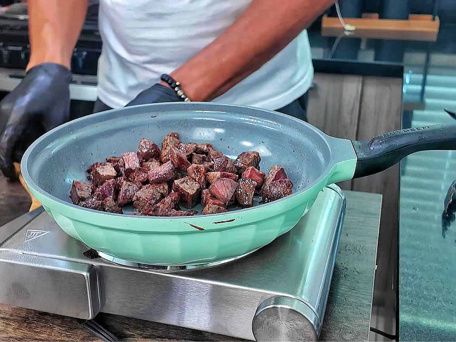 A bowl of creamy Parmesan mushroom orzo topped with perfectly seared steak bites and garnished with fresh parsley