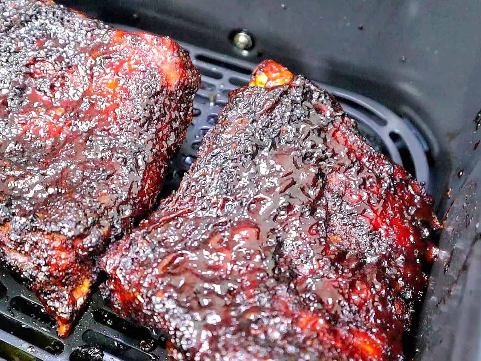 air fryer baby back ribs coated in a dark caramelized BBQ glaze