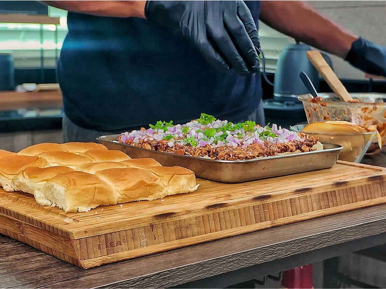 Baked BBQ chicken sliders made with Hawaiian rolls, shredded BBQ chicken, melted Gouda cheese, diced red onion, and cilantro, brushed with garlic herb butter.