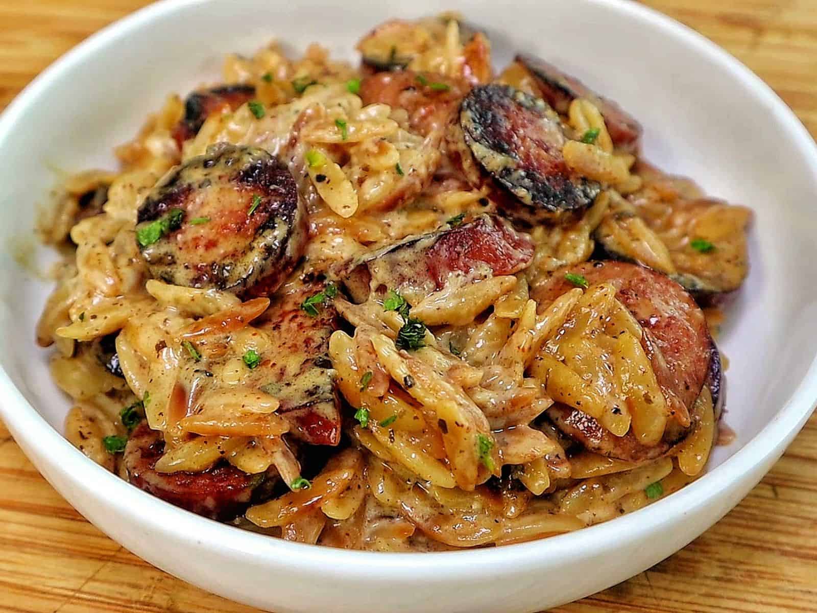 A creamy one-pot garlic butter orzo loaded with browned smoked sausage slices, freshly grated Parmesan cheese, and chopped parsley.