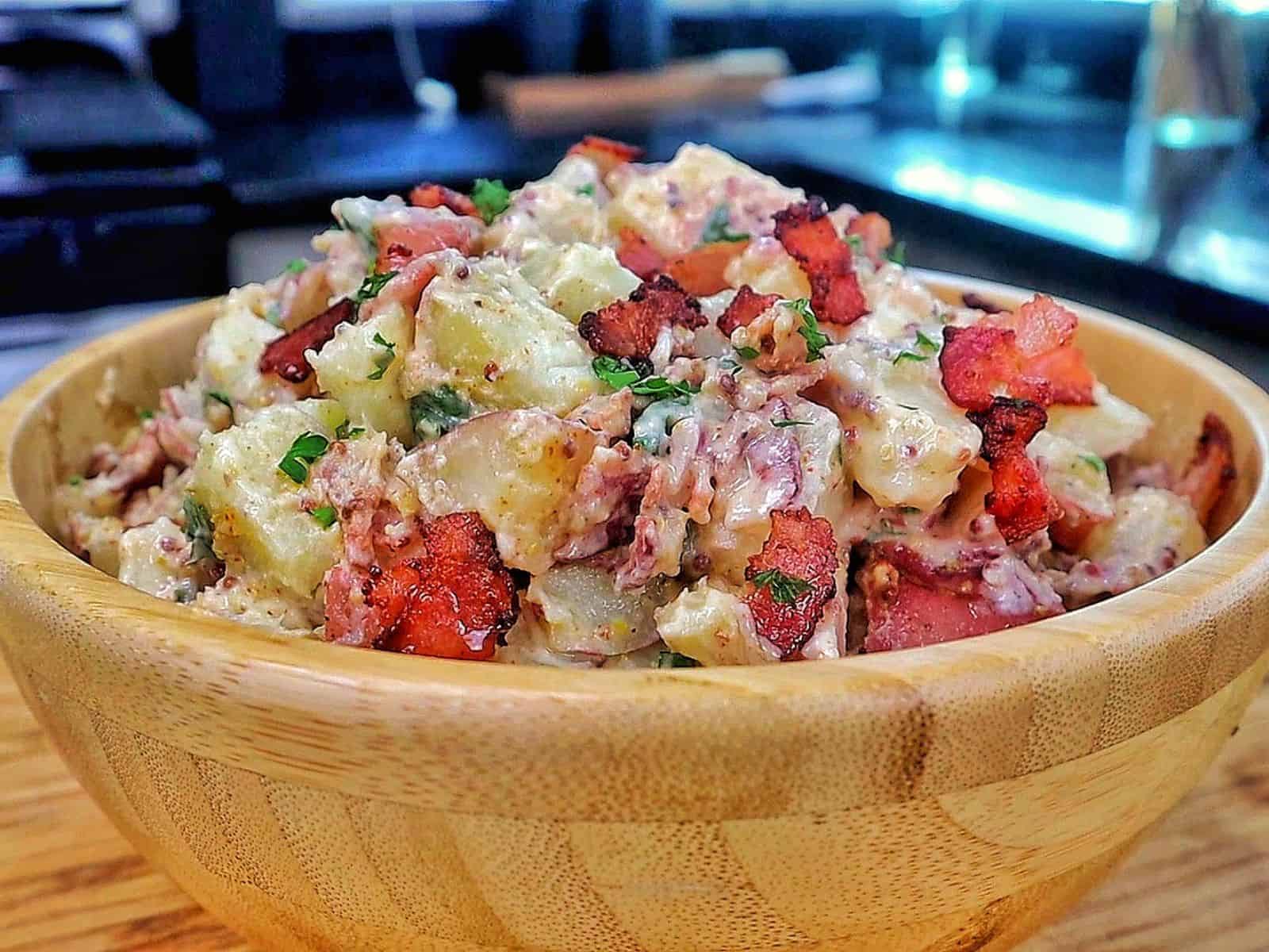 A creamy potato salad made with tender baby potatoes, crispy bacon, red onions, green onions, parsley, and a Dijon mayonnaise dressing.