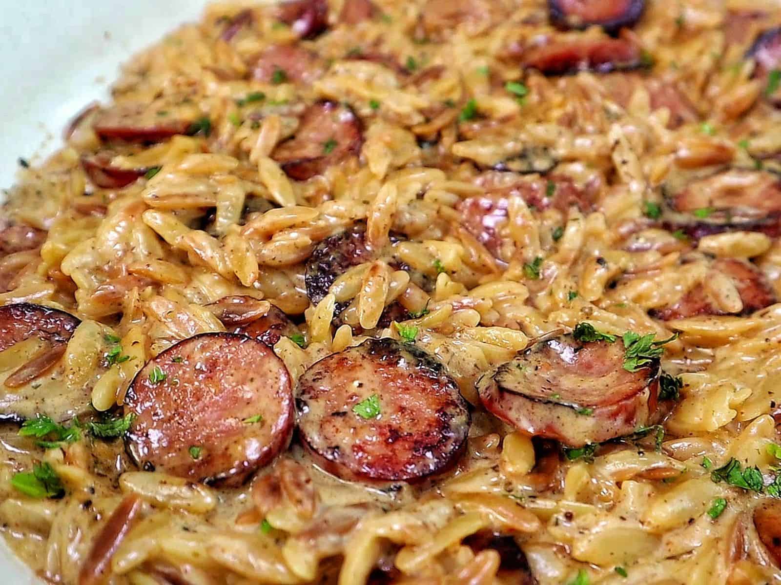 A creamy one-pot garlic butter orzo loaded with browned smoked sausage slices, freshly grated Parmesan cheese, and chopped parsley.