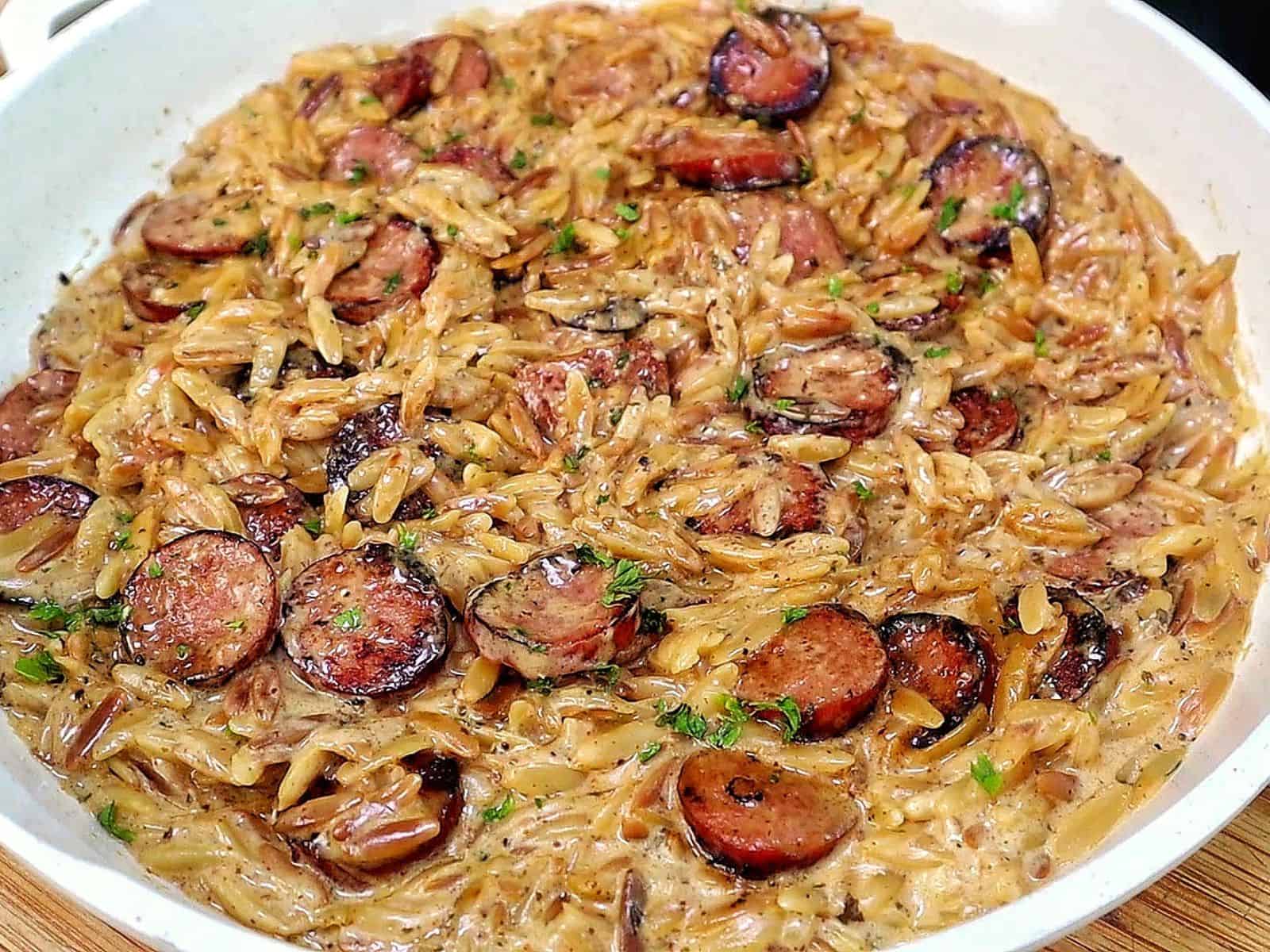 A creamy one-pot garlic butter orzo loaded with browned smoked sausage slices, freshly grated Parmesan cheese, and chopped parsley.
