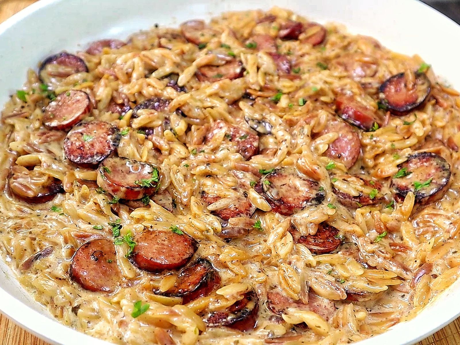 A creamy one-pot garlic butter orzo loaded with browned smoked sausage slices, freshly grated Parmesan cheese, and chopped parsley.