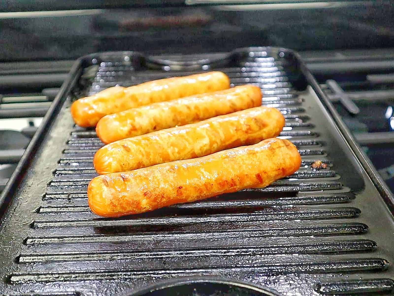 grilled hot dogs in toasted buns topped with melted sharp cheddar cheese, diced red onions, fresh cilantro, jalapeños, and creamy spicy firecracker sauce.
