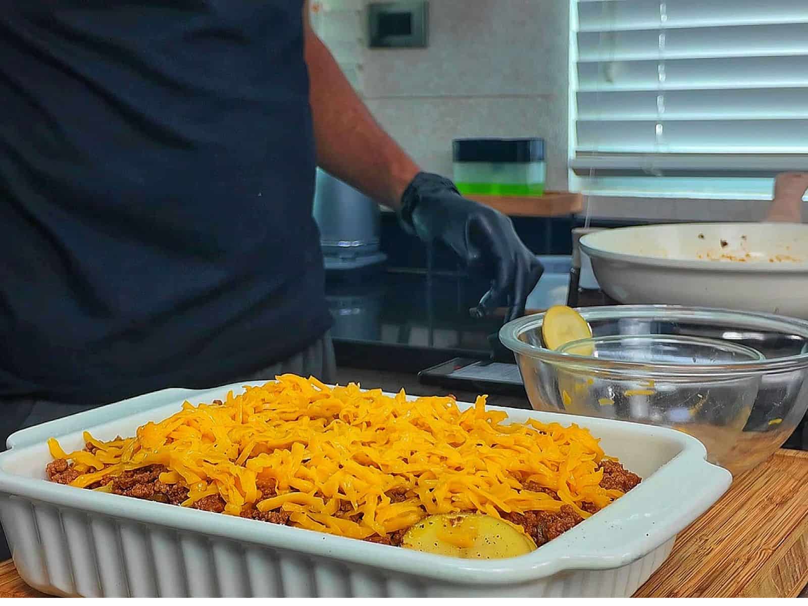 A cheesy Taco Potato Bake made with layers of seasoned ground beef, tender sliced potatoes, salsa, melted Mexican cheese, and topped with fresh green onions and sour cream.