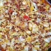 Ground beef and chopped cabbage cooked together in a cast-iron skillet with diced tomatoes, onions, garlic, and seasonings, finished with red pepper flakes for an easy one-pan dinner.